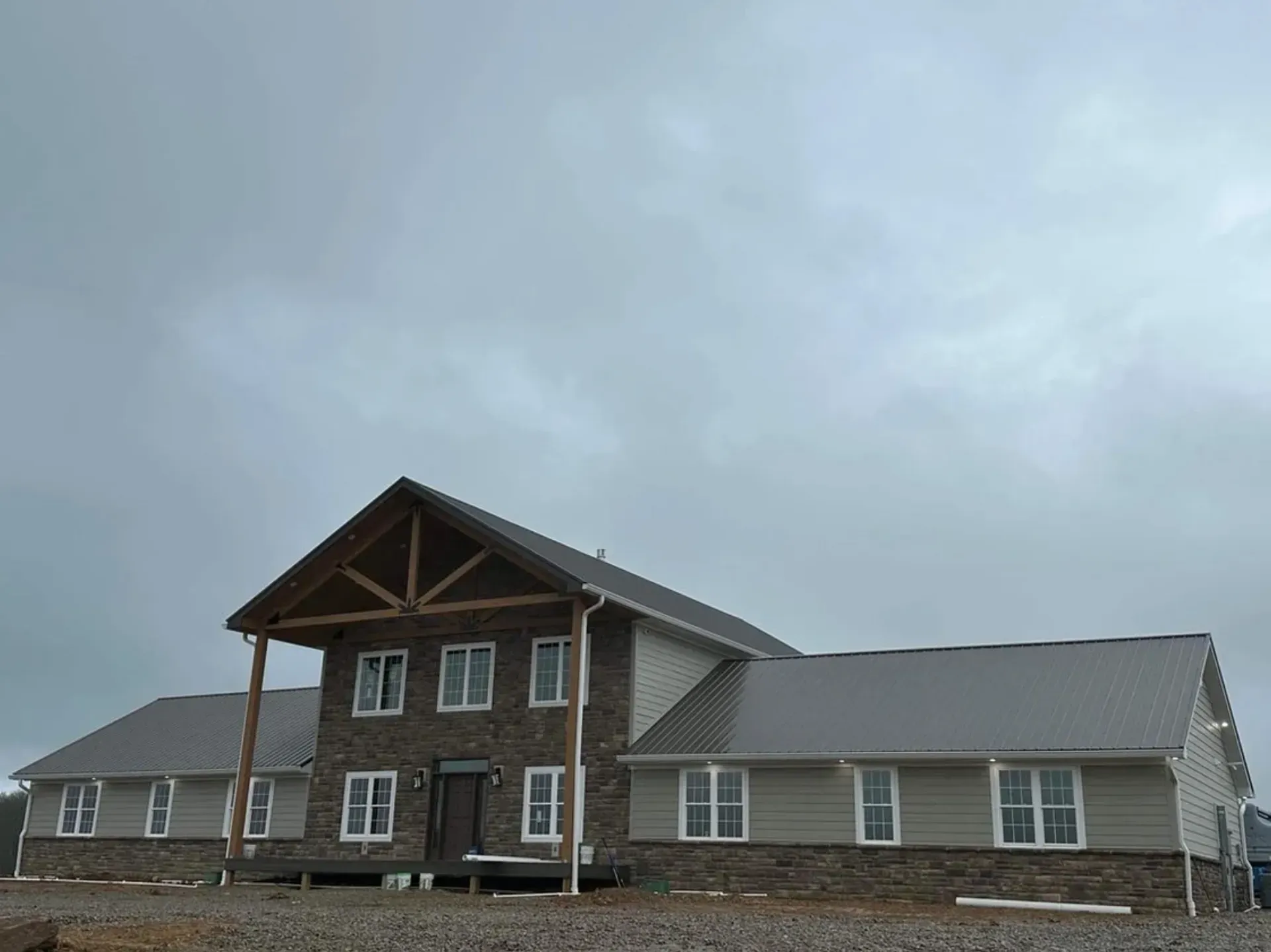 A large house with a gray roof and a porch on a cloudy day.