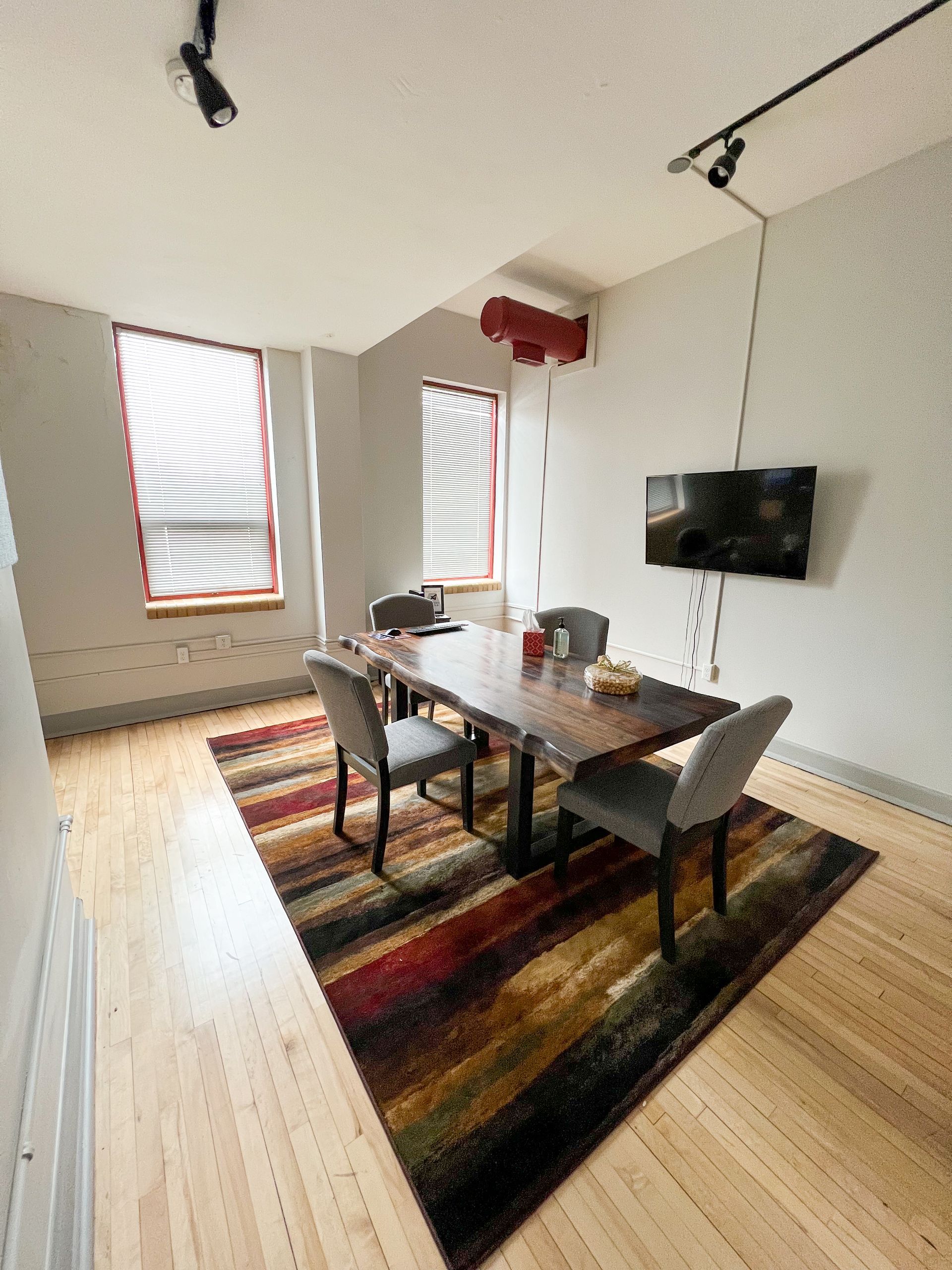 A dining room with a table and chairs and a television on the wall.