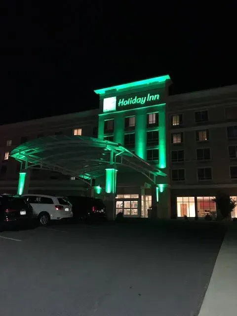 A holiday inn is lit up green at night