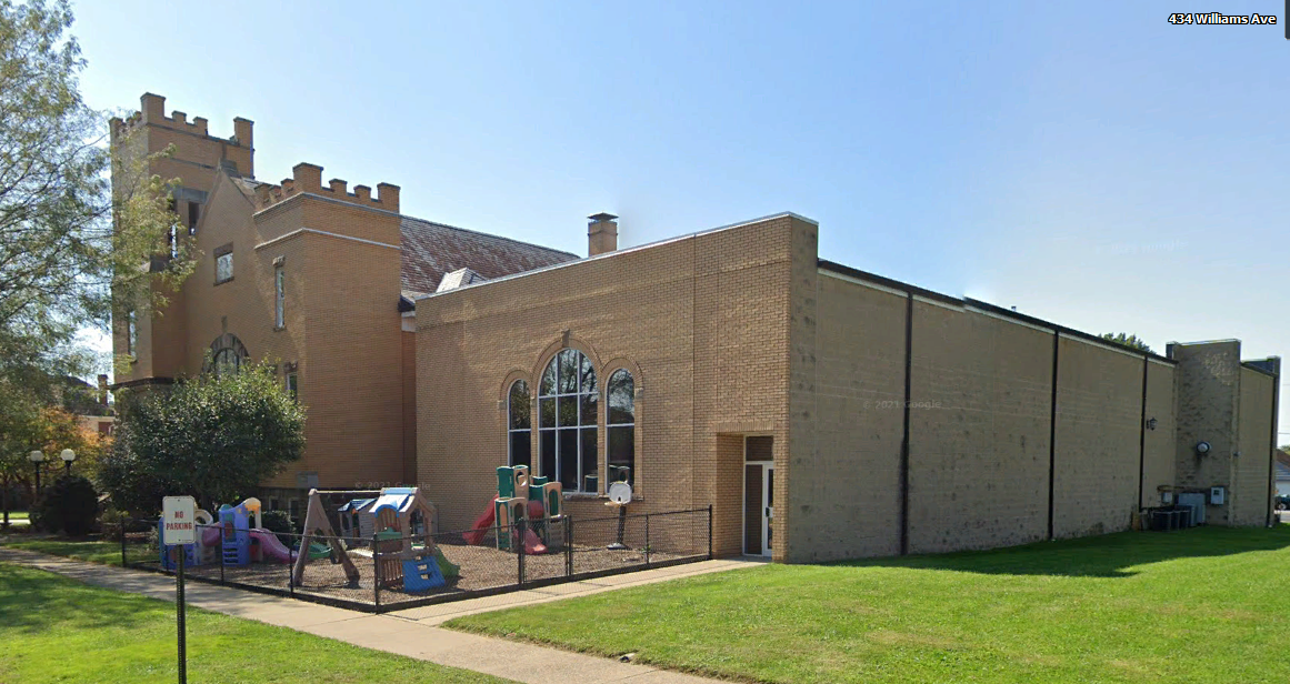 A large brick building with a playground in front of it.