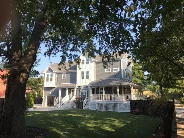 A large house with a large porch is surrounded by trees.