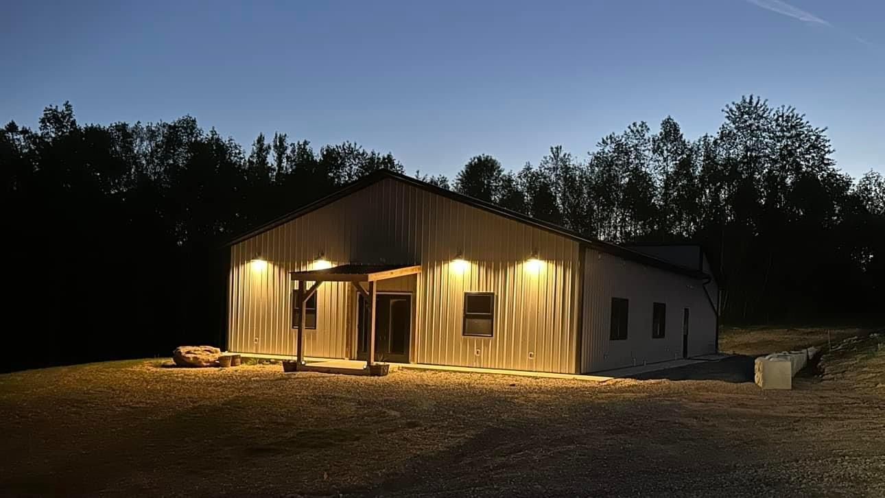 A house is lit up at night in the middle of a field.