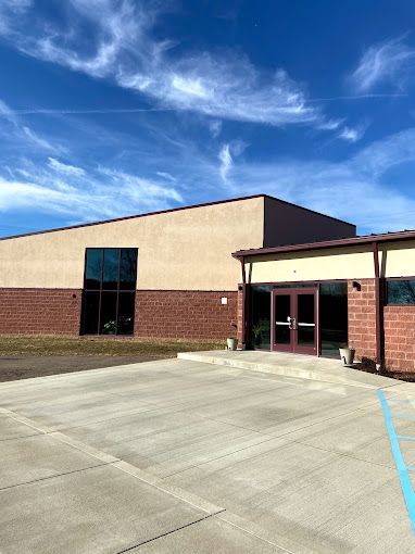 A large brick building with a parking lot in front of it on a sunny day.