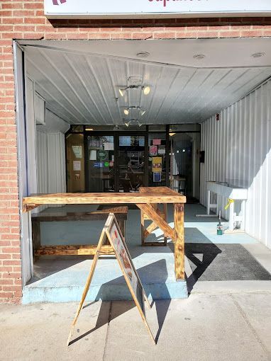 A wooden table is sitting in front of a brick building.
