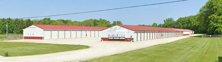 A row of white buildings with red roofs are lined up in a field.