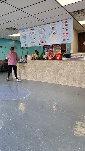 A woman is standing in front of a counter in a restaurant.