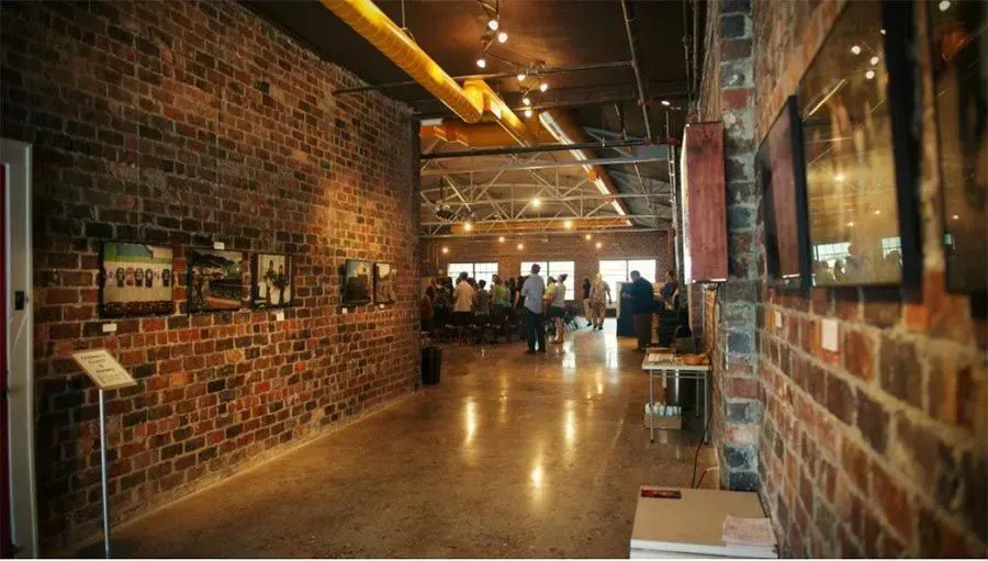 A long hallway with a brick wall and pictures on the wall.