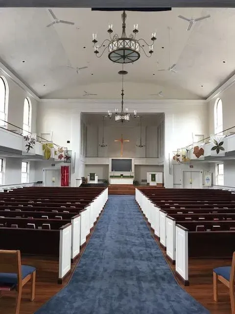 The inside of a church with rows of pews and a chandelier hanging from the ceiling