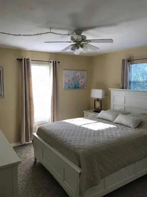 A bedroom with a large bed and a ceiling fan