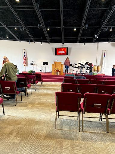 A large auditorium filled with red chairs and a podium.