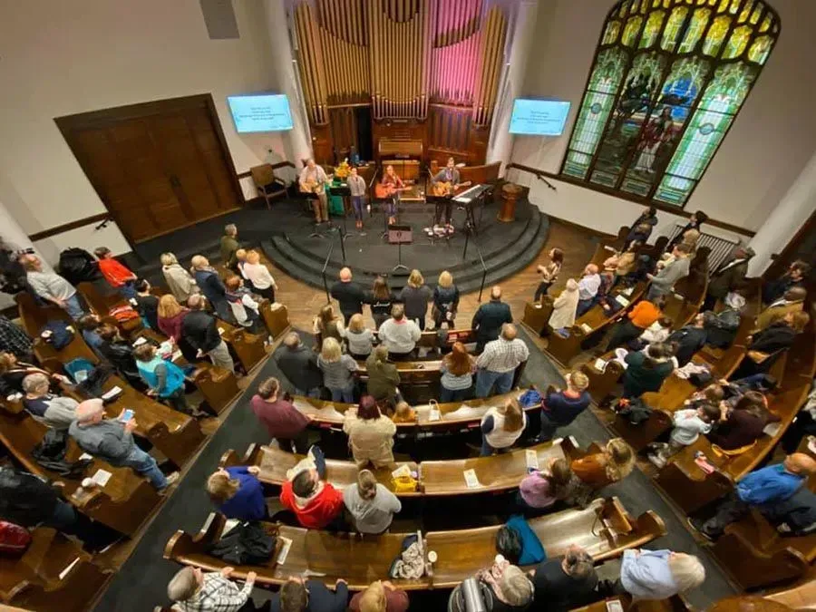 A large group of people are sitting in a church watching a concert.