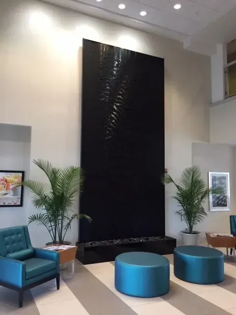 A living room with blue chairs and ottomans and a large black wall