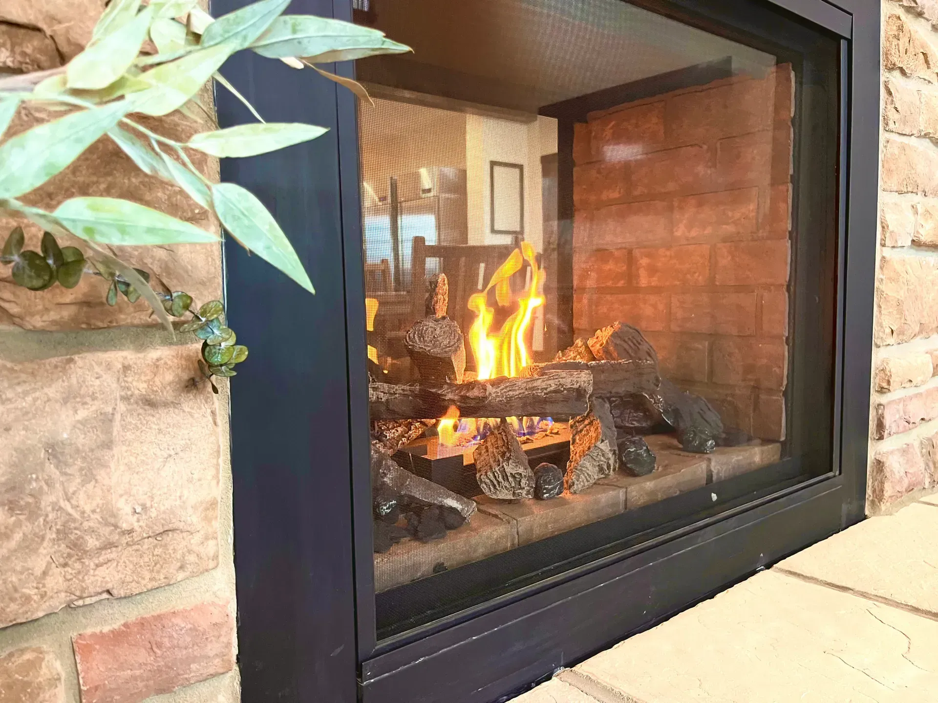 A fireplace is built into a brick wall with a glass door.