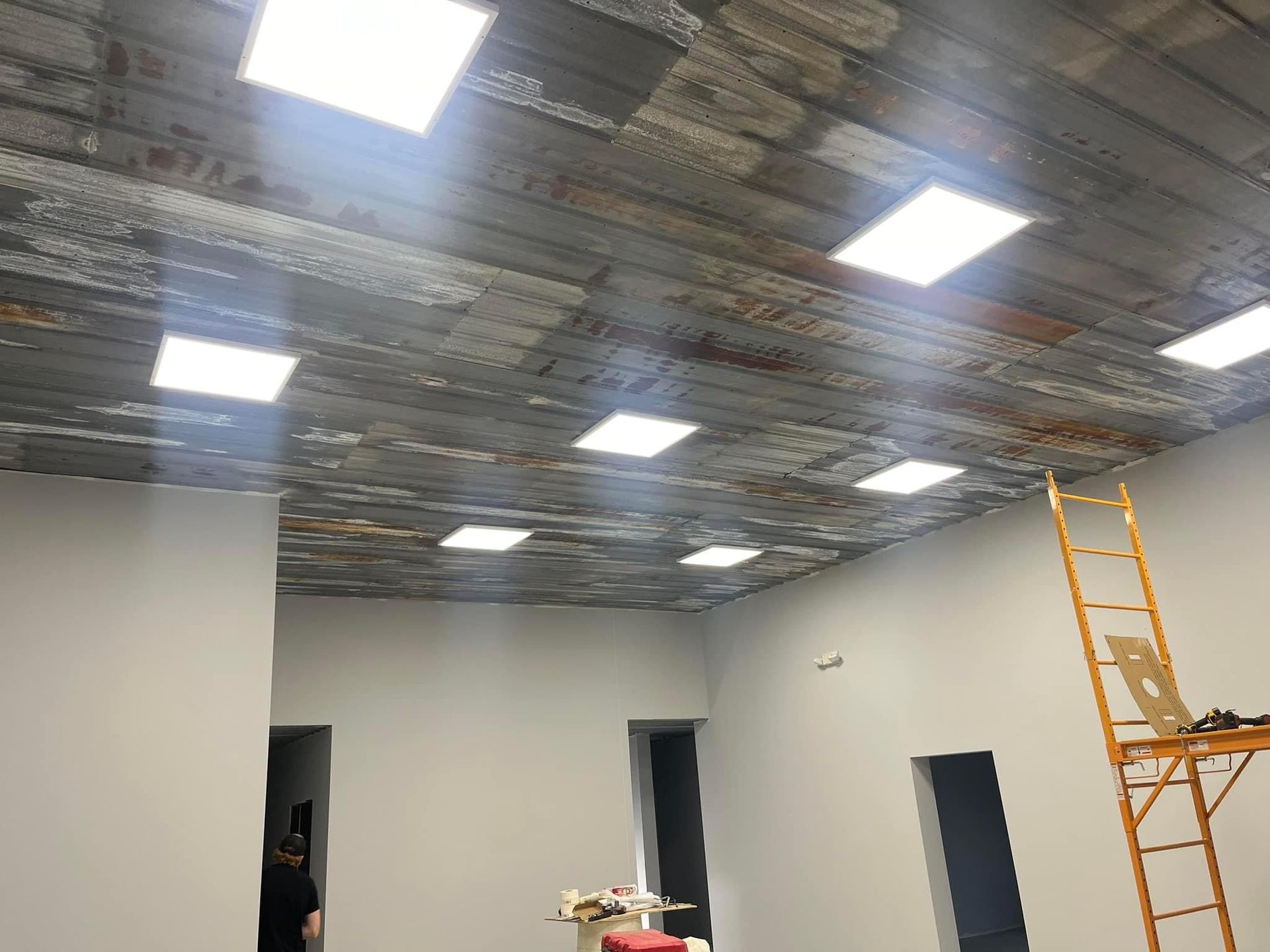 A room with a ladder and lights on the ceiling.