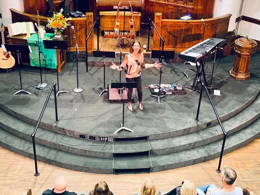 A woman is singing into a microphone on a stage in front of a crowd.