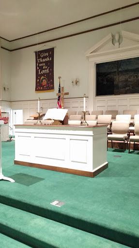 A church with a white altar and green carpet.