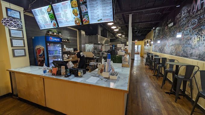 The inside of a restaurant with tables and chairs and a counter.