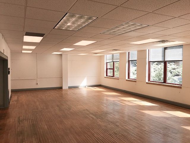 An empty room with hardwood floors and lots of windows