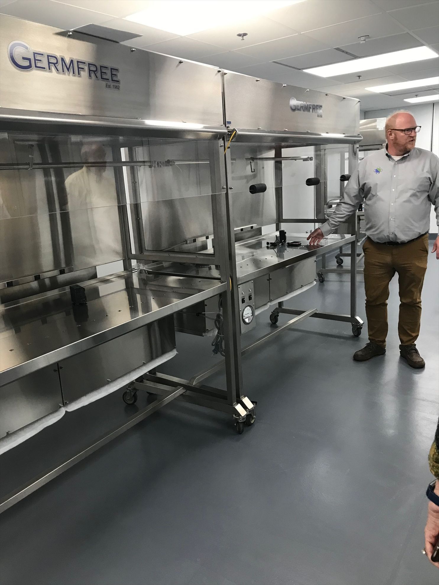 A man is standing in front of a large stainless steel machine.