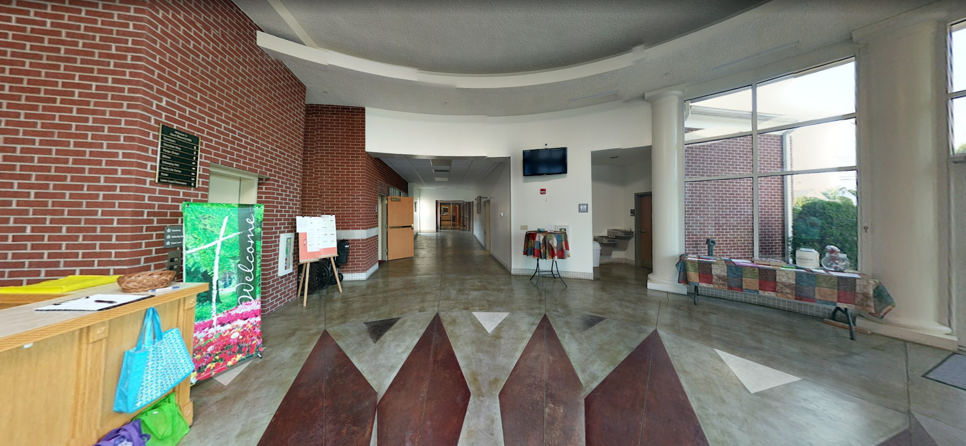 A long hallway with a brick wall and a large window.