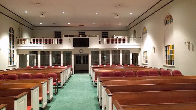 An empty church with wooden benches and red seats