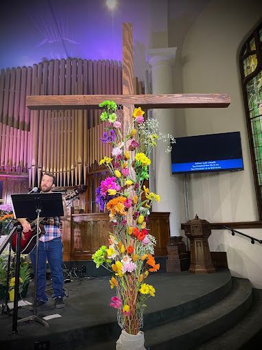 A man is singing into a microphone in front of a cross in a church.