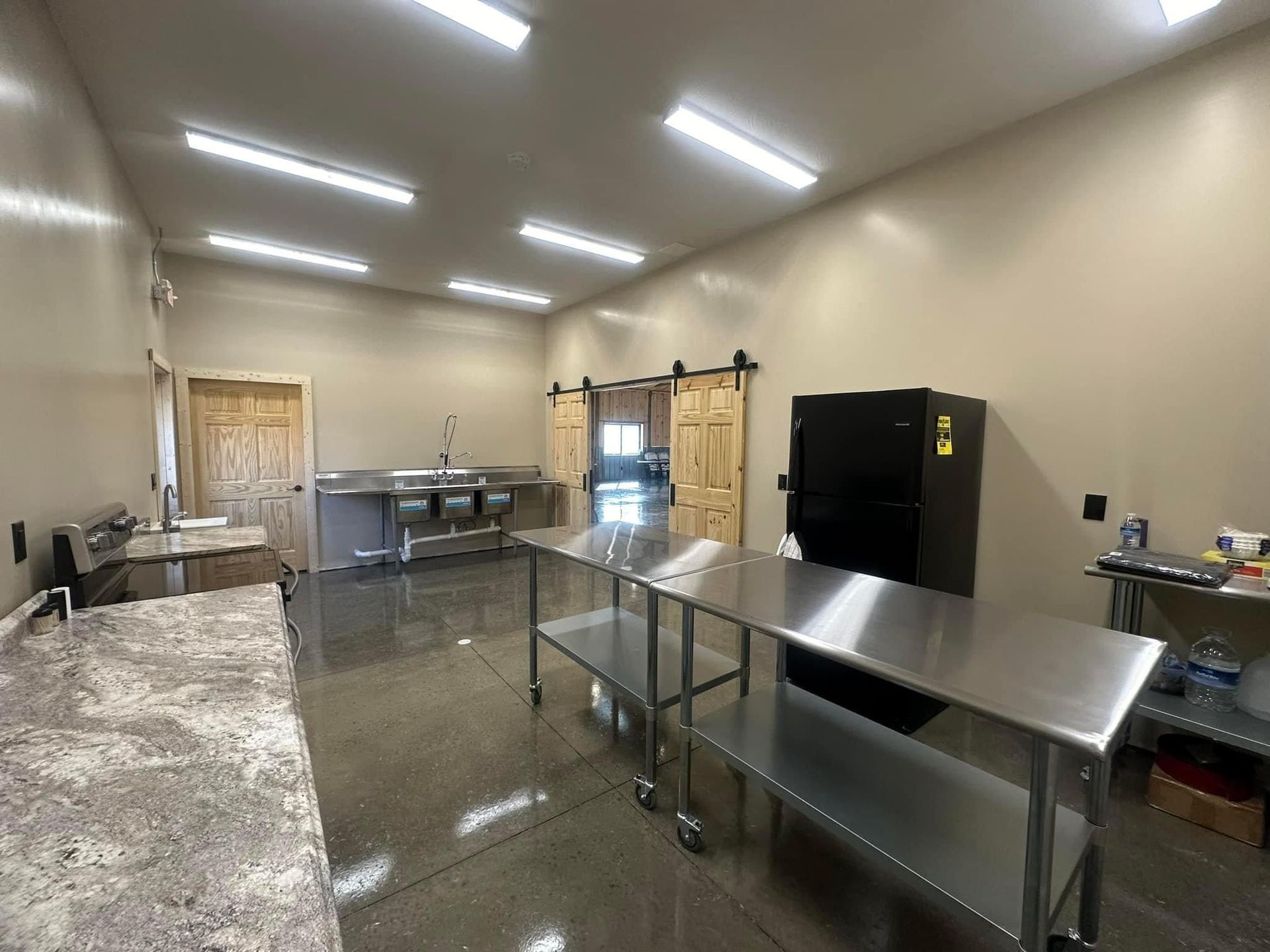 A large kitchen with stainless steel tables and a refrigerator.