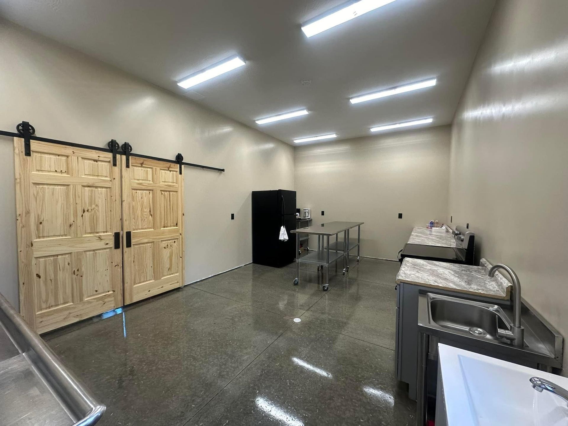 A large room with sliding barn doors and a sink.