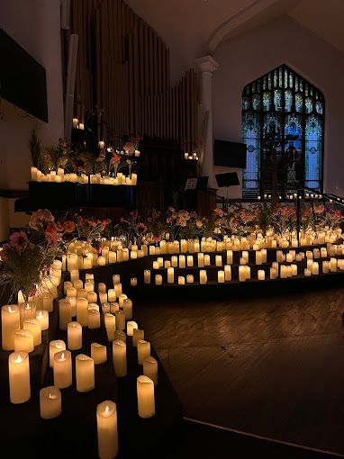 A church filled with lots of lit candles and flowers.