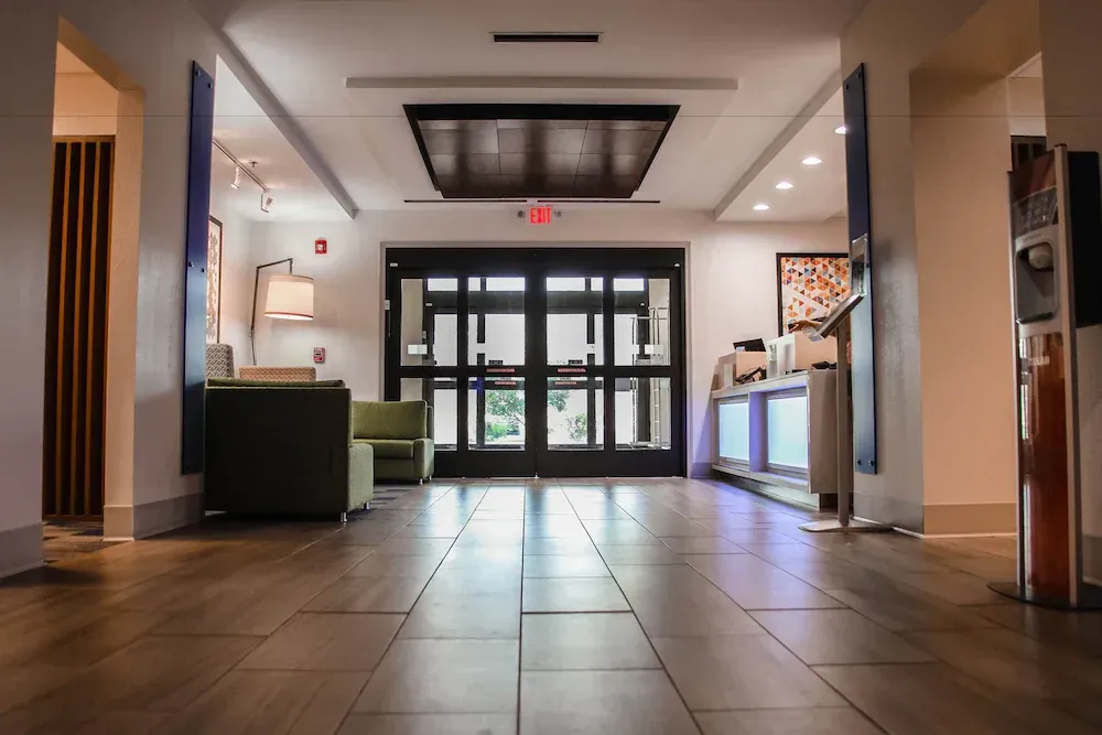 A hotel lobby with a wooden floor and a red exit sign