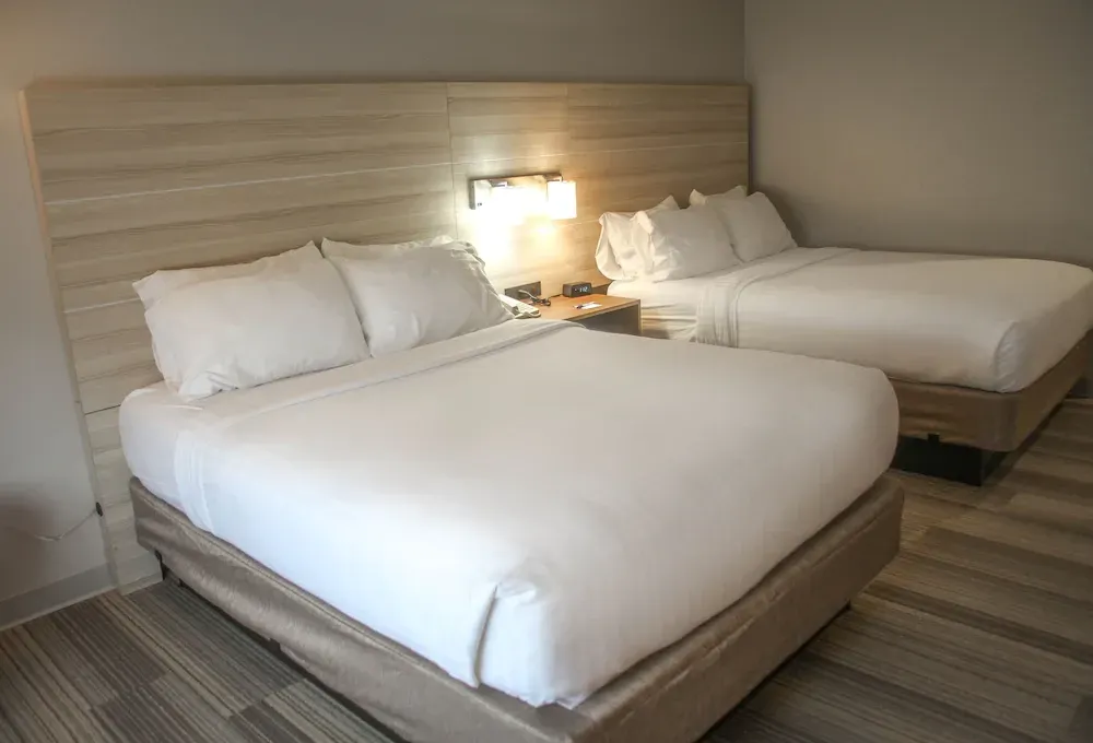 A hotel room with two beds and a wooden headboard.
