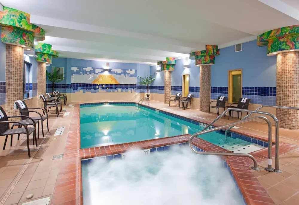 A large indoor swimming pool with a jacuzzi in the middle.