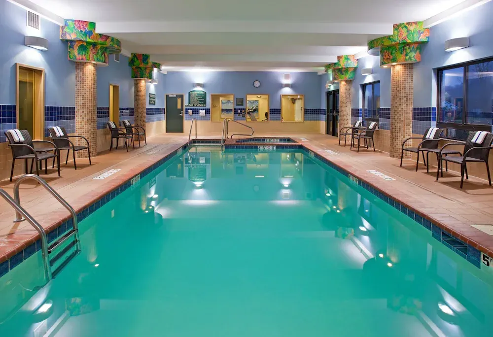 A large indoor swimming pool with chairs and tables around it.
