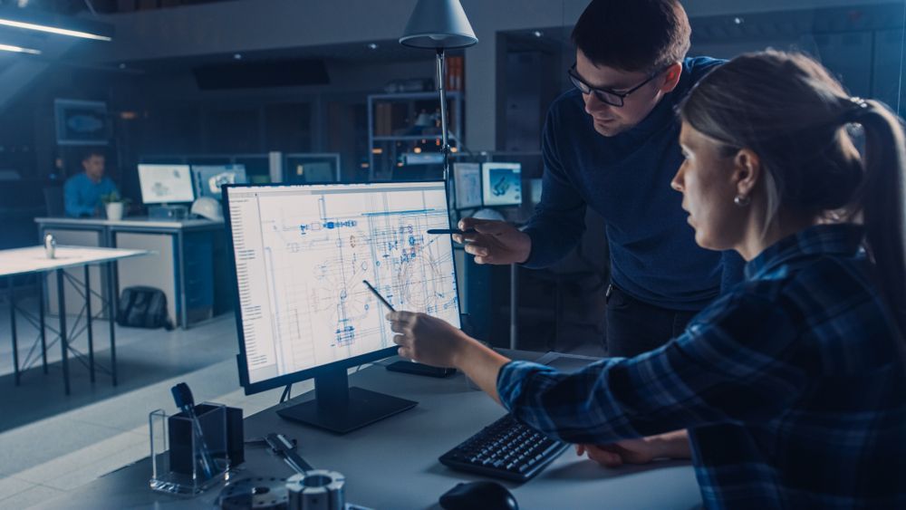 A man and a woman are looking at a computer screen.