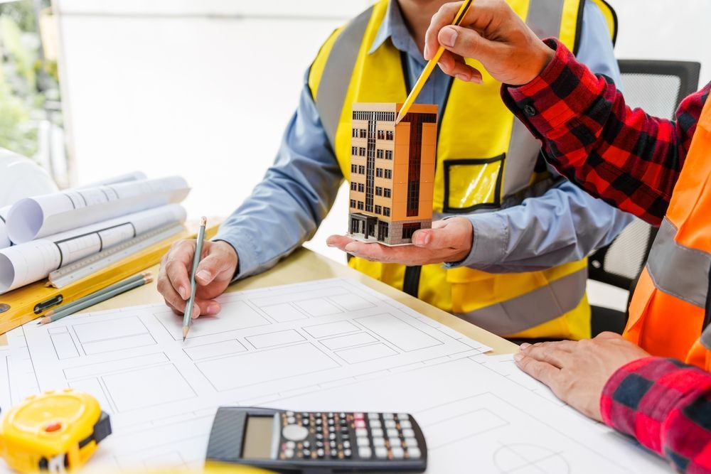 Two men, including a male Asian construction contractor engineer, discuss structural plans and engineering.