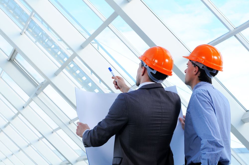 Two men wearing hard hats are looking at a blueprint.