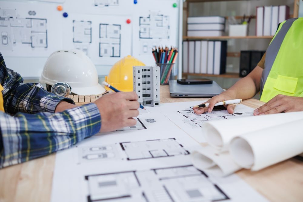 Group of architects are sitting around a table looking at blueprints.