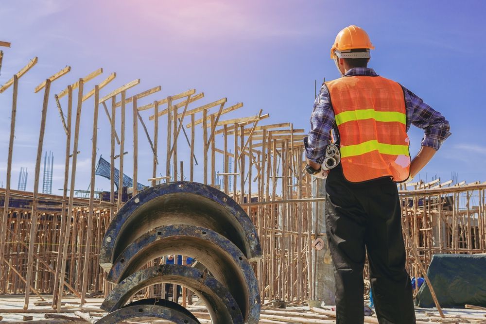 Architect is holding a blueprint while checking the construction site.