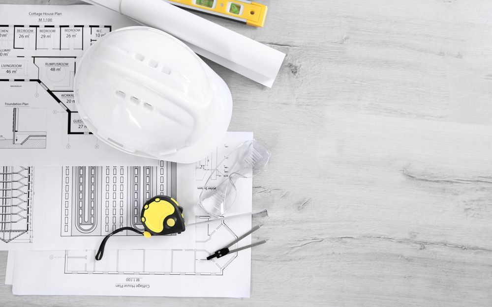 A hard hat is sitting on top of a wooden table next to a tape measure.