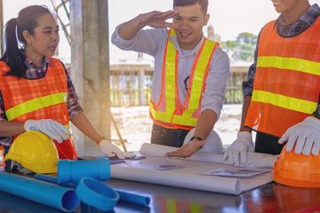 Structural engineer or architect and foreman worker with blueprints talking to each other.