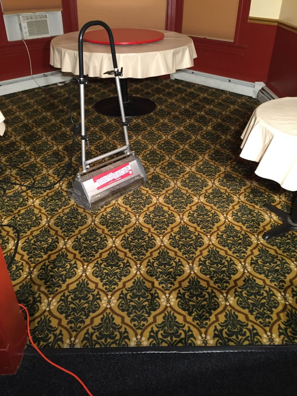 A vacuum cleaner is sitting on a carpet in a room with tables