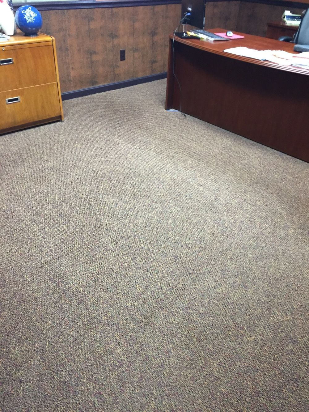 A room with a desk and a bowling ball on the floor.