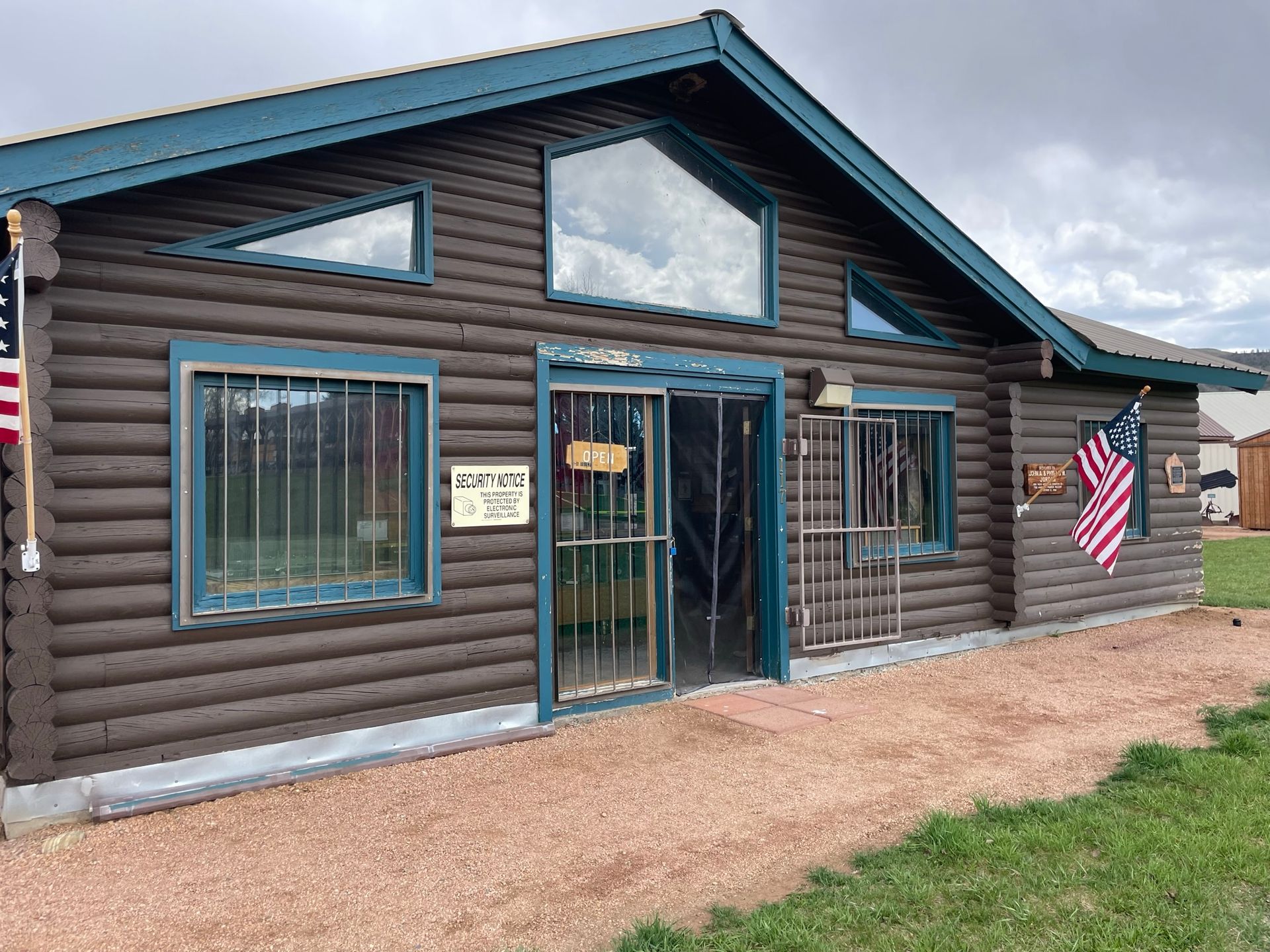 A log cabin with an american flag on the side of it.