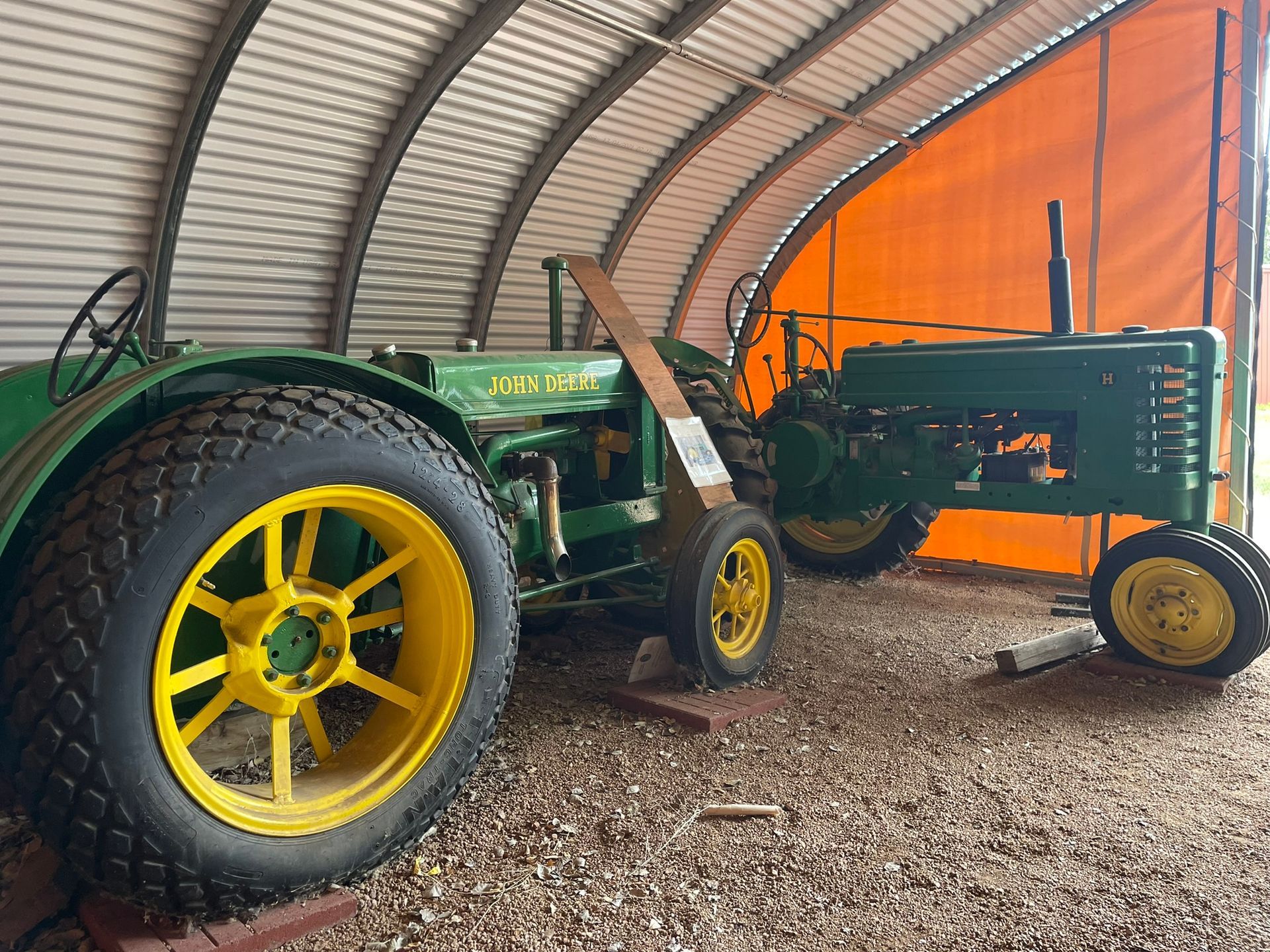 Two john deere tractors are parked in a shed