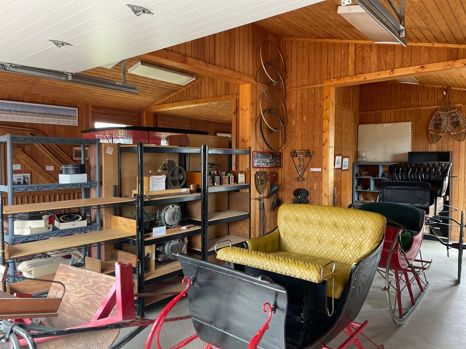 A sleigh is sitting in a garage next to shelves.