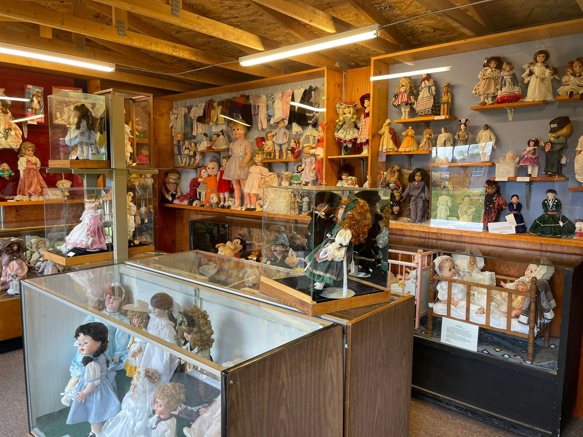 A room filled with lots of dolls and display cases.