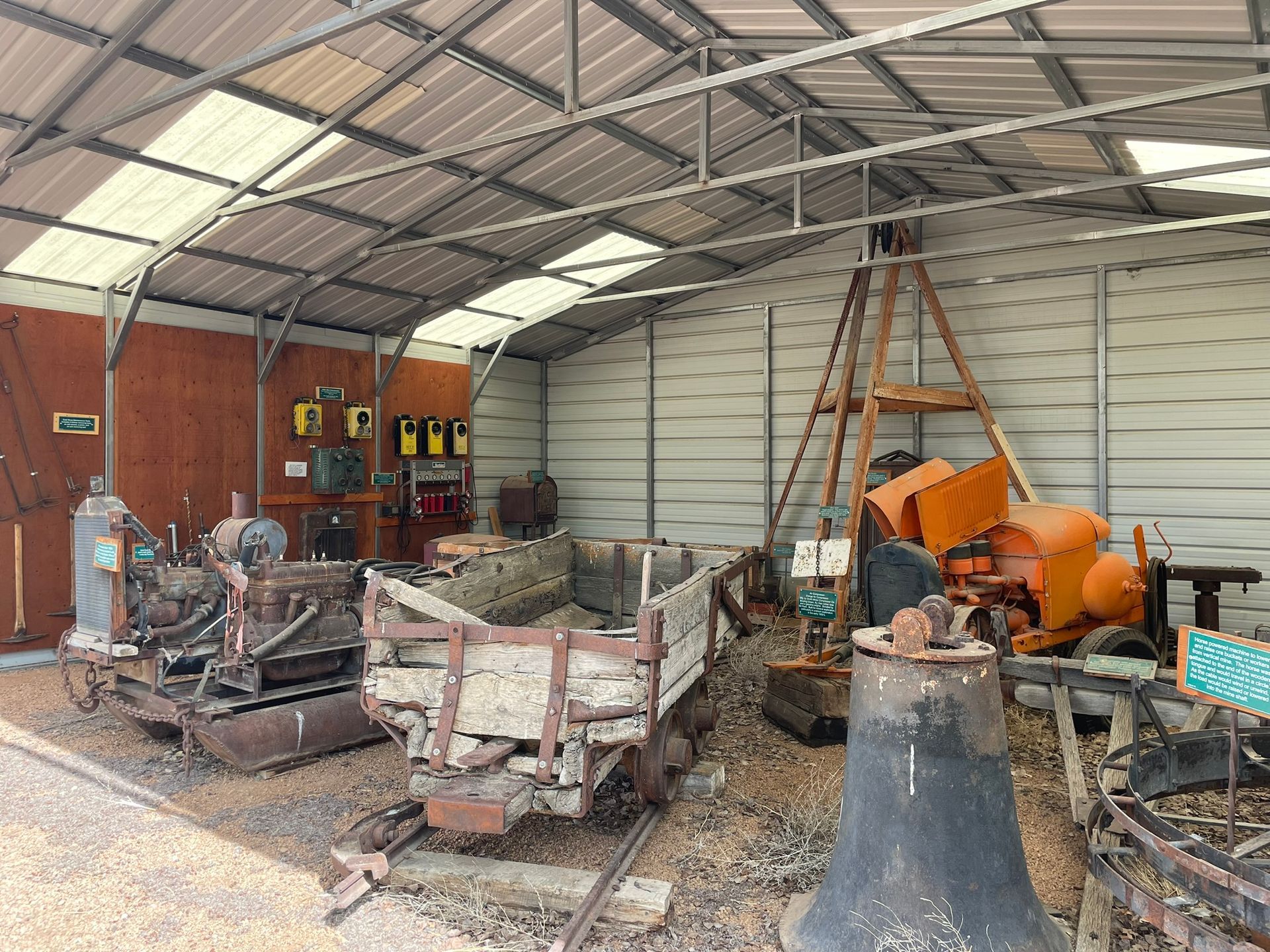 A shed filled with lots of old machinery and a bell.
