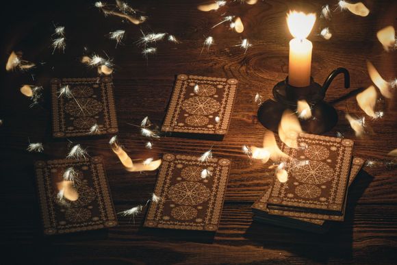 una candela è seduta su un tavolo di legno accanto a un mucchio di carte da gioco .