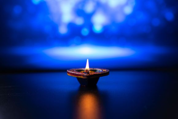 una candela è accesa su un tavolo con uno sfondo blu .