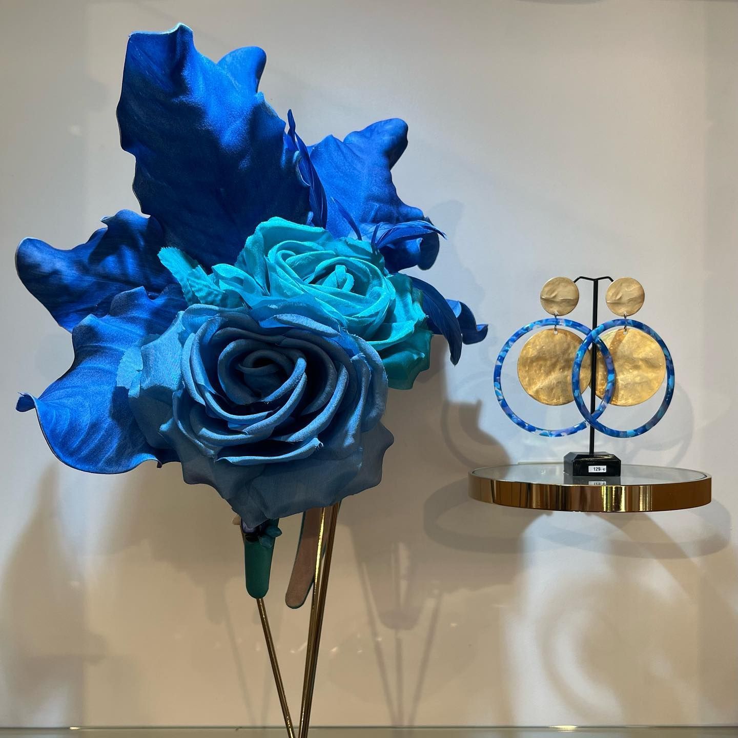 un bouquet de roses bleues est assis à côté d' une paire de boucles d' oreilles